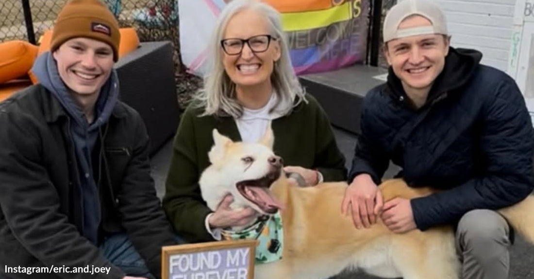 Two young men and an older woman smiling with a newly adopted dog while holding a “Found My Furever @ Tails Rescue” sign outdoors.