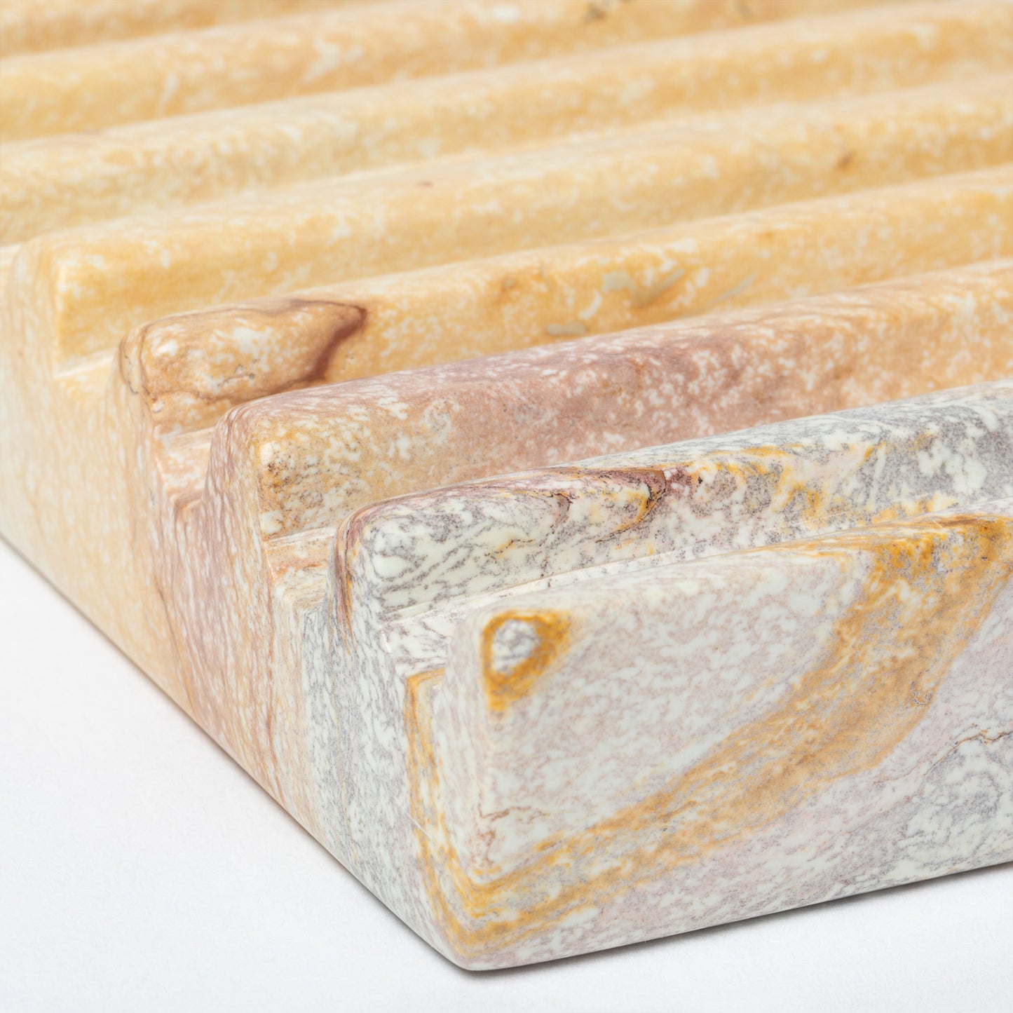 Close-up of a soapstone soap dish with a textured surface on a white background.