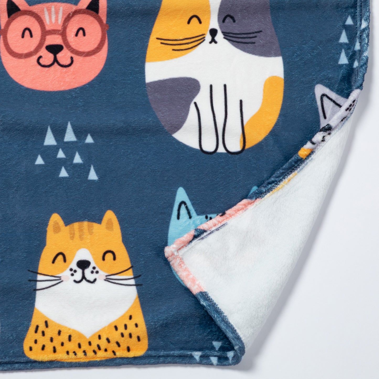 Close up of a plush fleece blanket with a cat design, and a plain white backing.