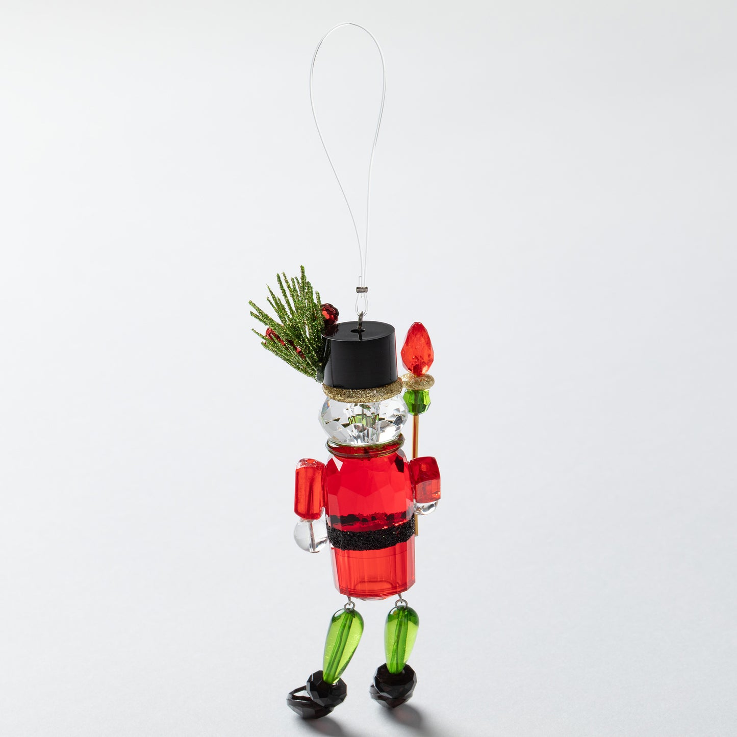 Decorative Christmas nutcracker ornament with holly on hat on a white background
