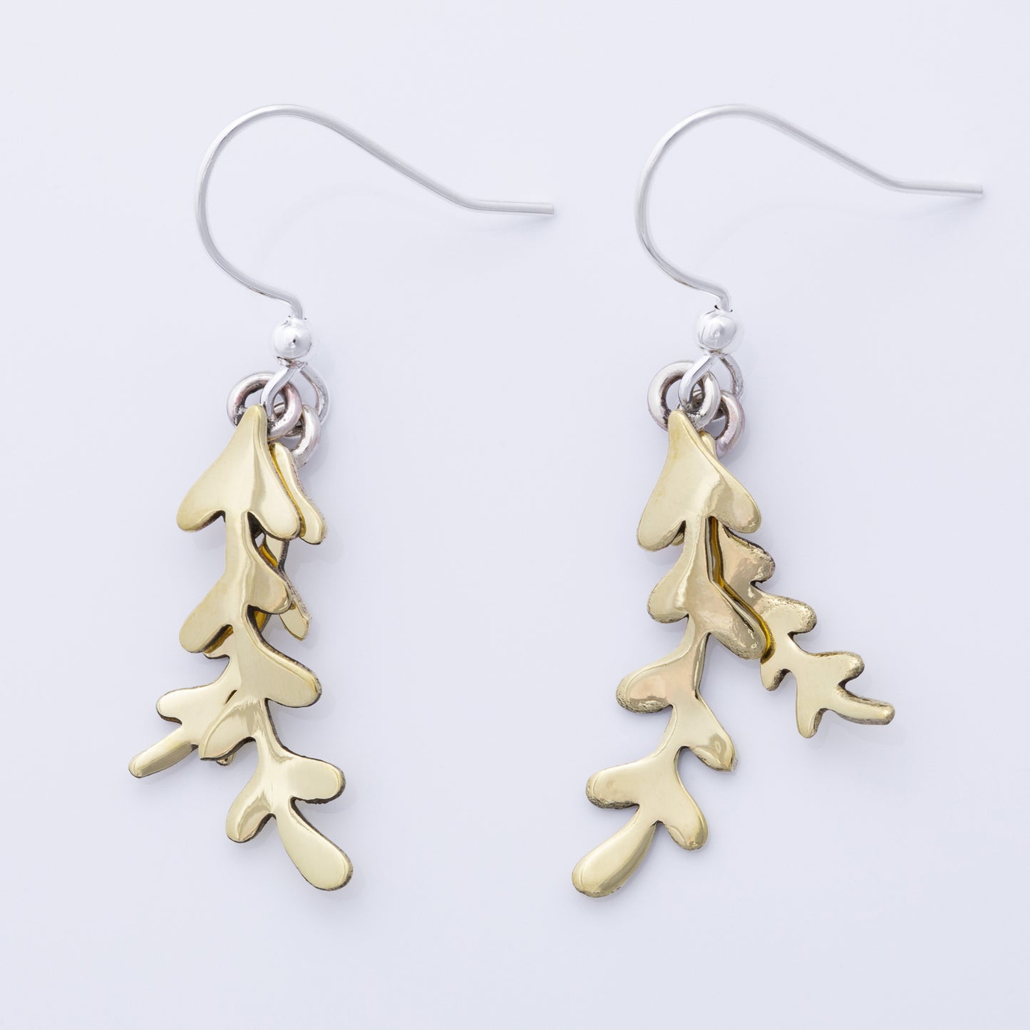 Brass leaf-shaped earrings on a white background