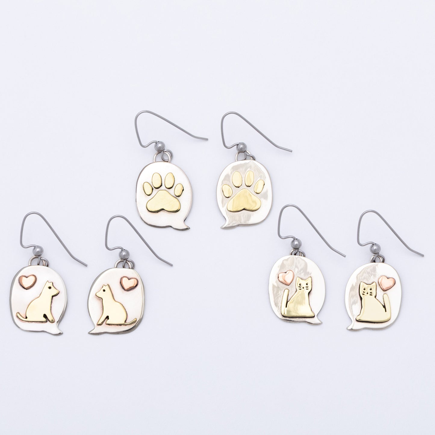 Set of earrings with paw prints and animal illustrations on a light gray background.