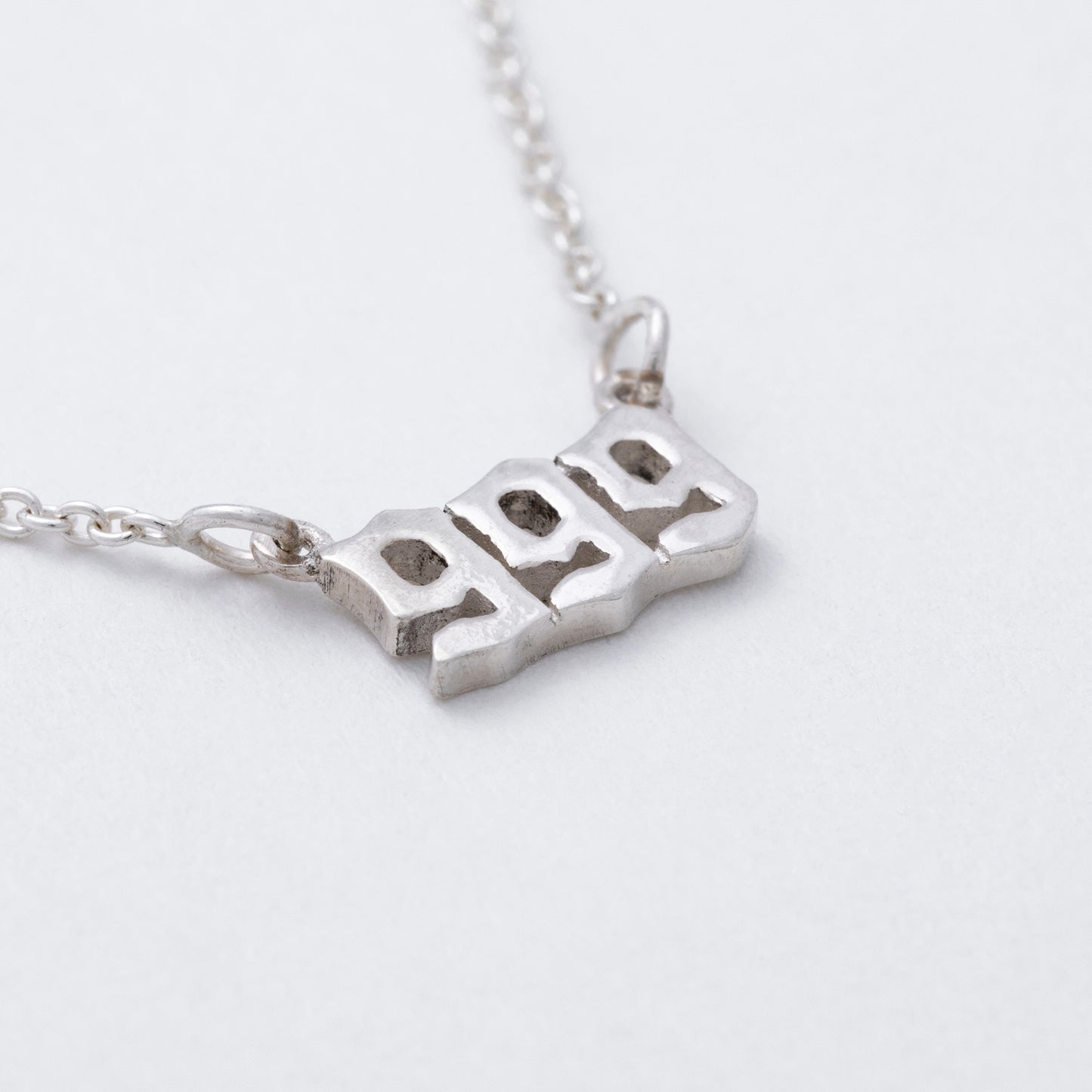 Silver necklace with a 999 pendant on a light gray background