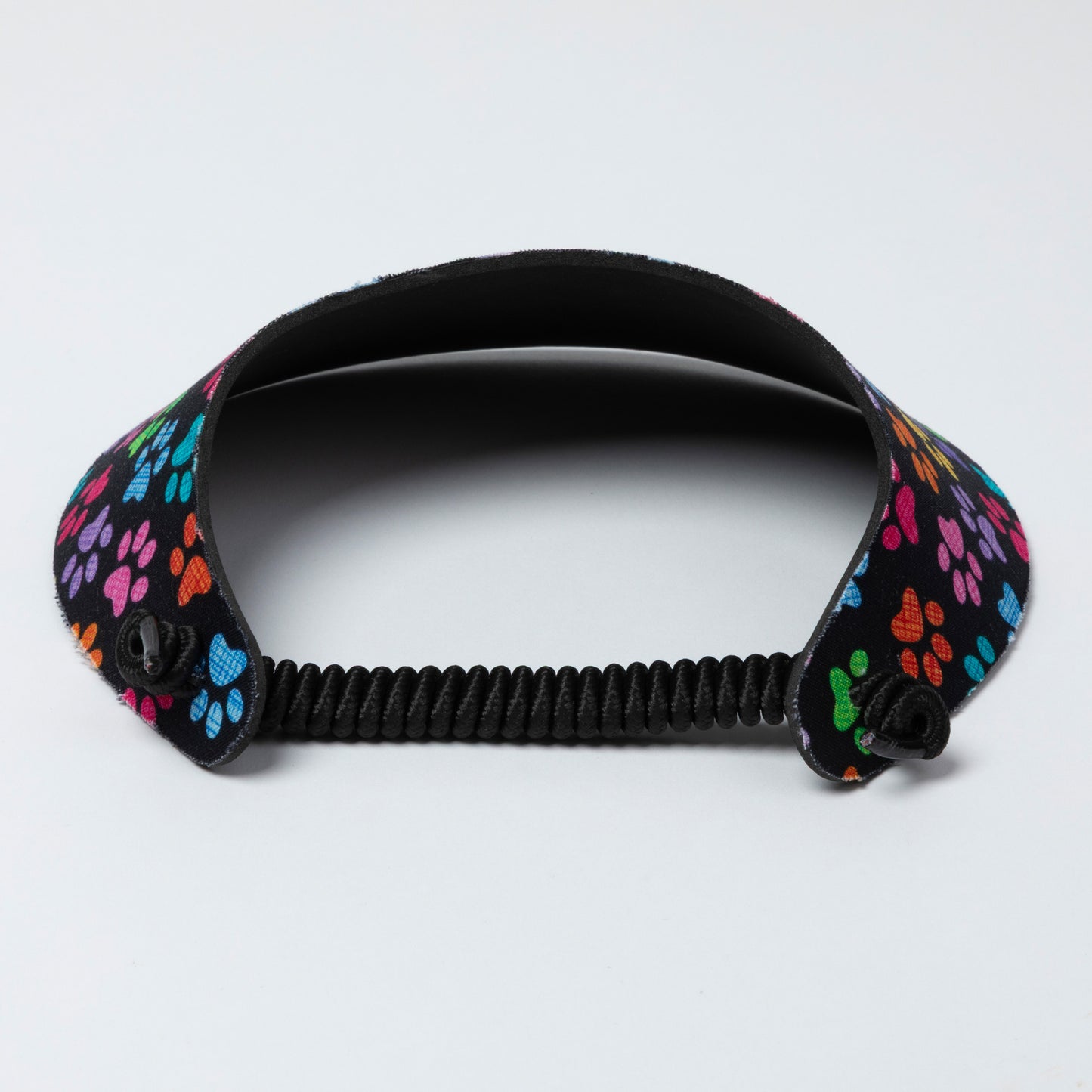 Black visor with colorful paw print design on a light gray background