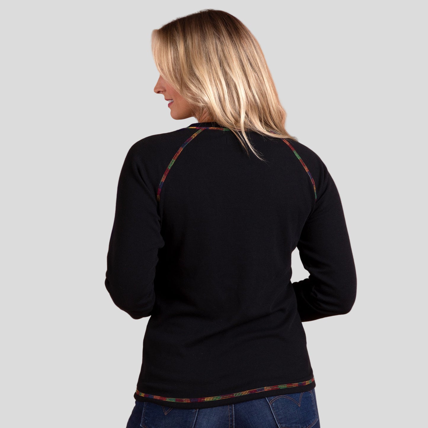 Woman wearing a black thermal top with colorful trim on a gray background