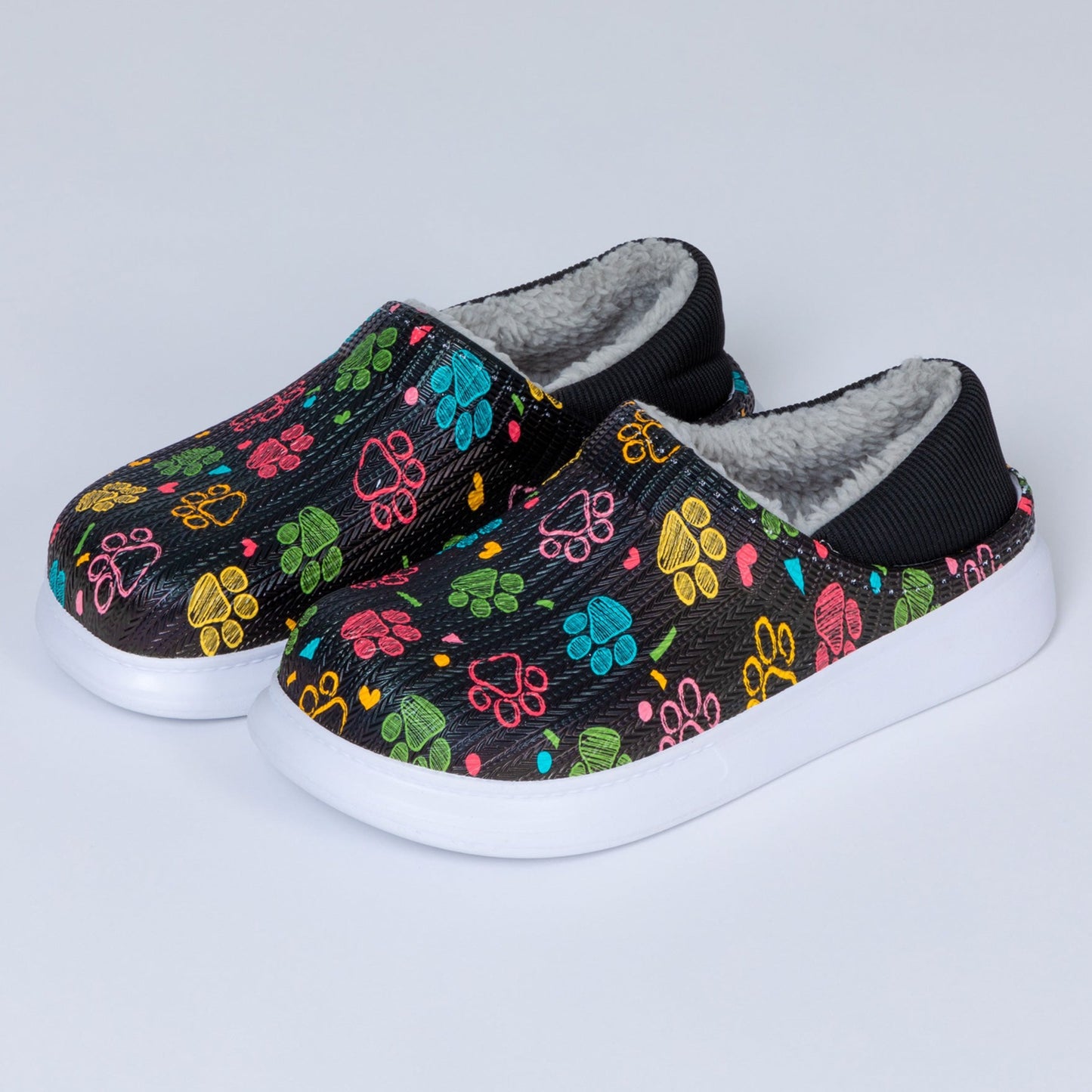 Slipper shoes with faux fur lining, featuring a paw-printed pattern in an array of colors, on a white background.