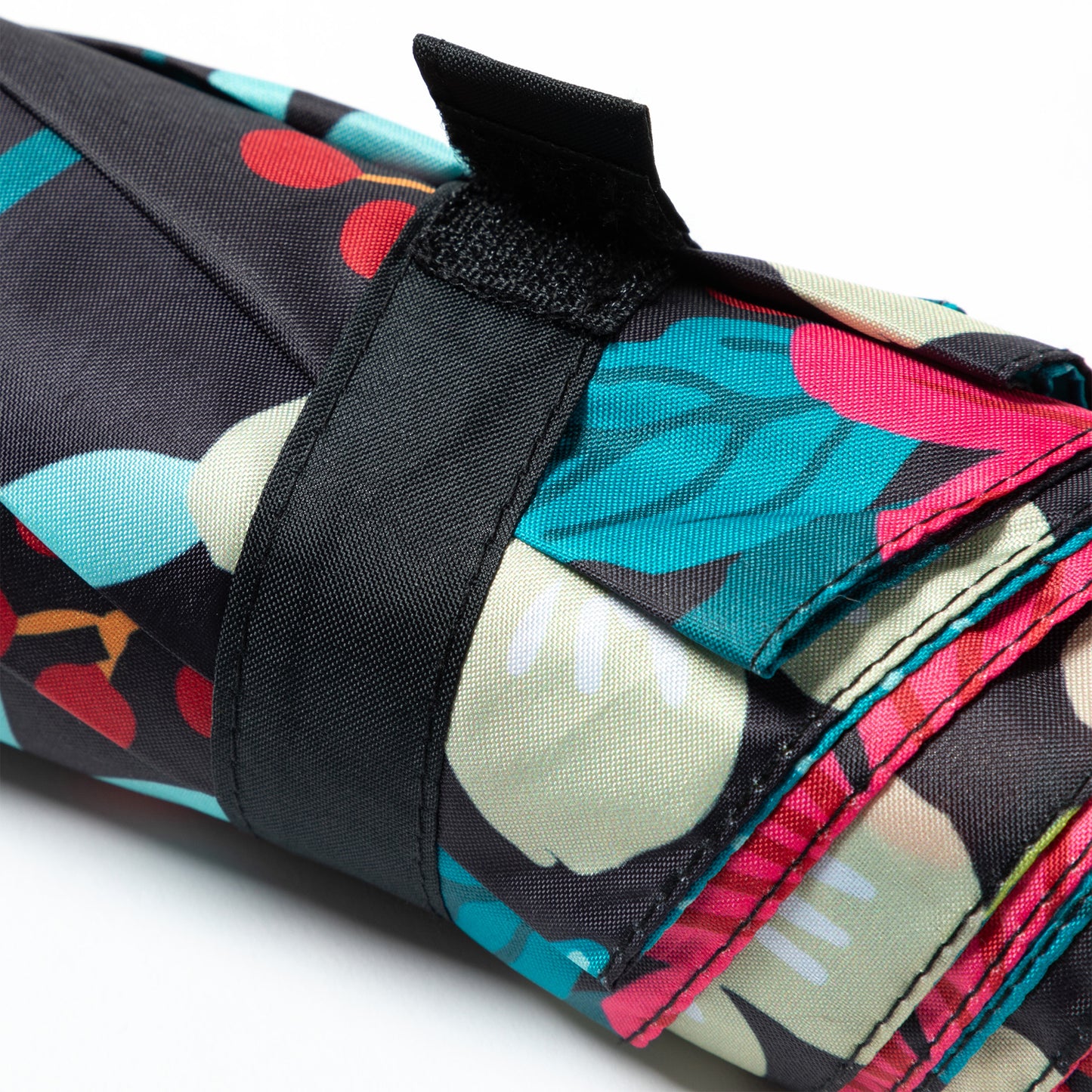 Colorful, folded umbrella with floral patterns secured by a black strap.