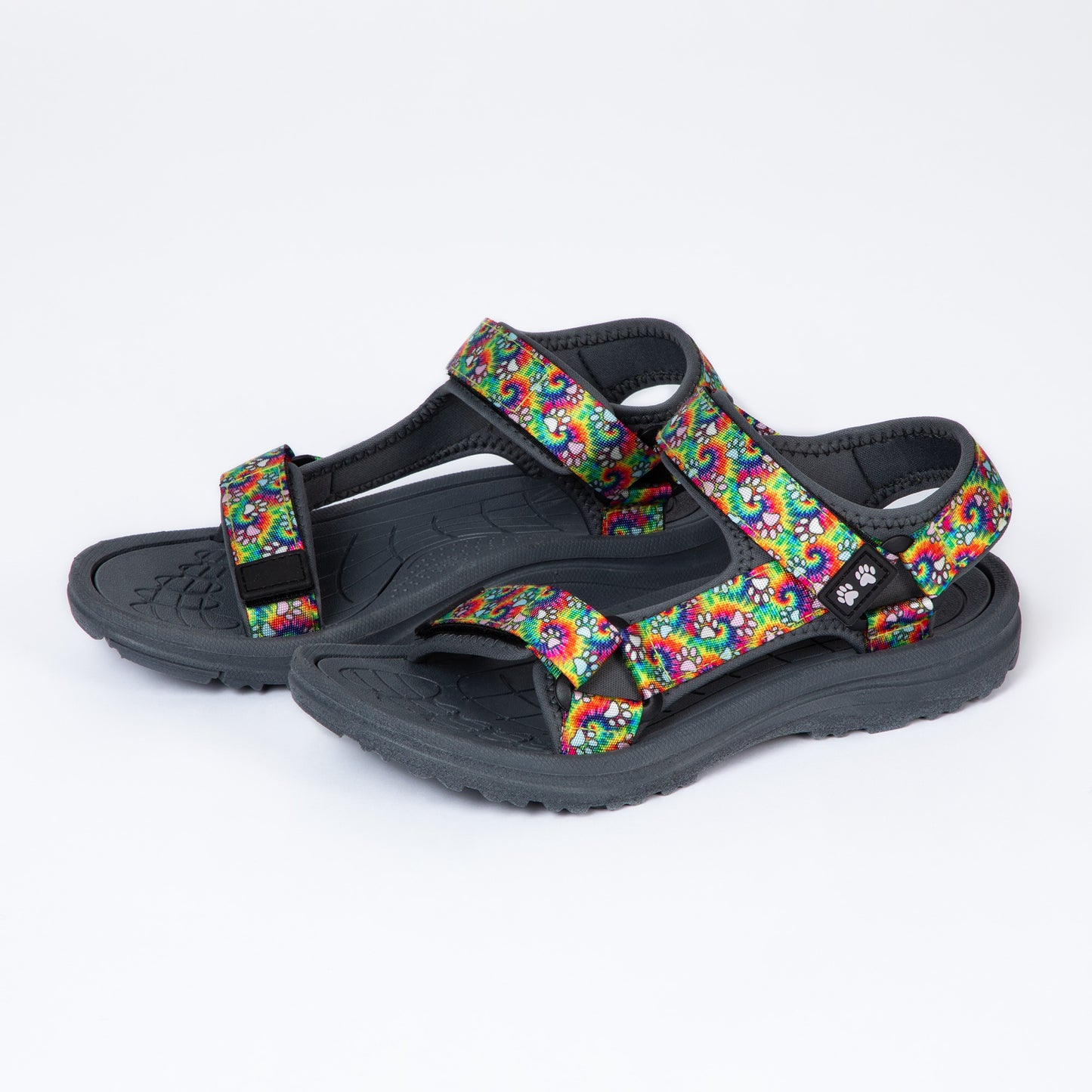Colorful tie-dye sandals with adjustable straps and a textured sole on a white background.