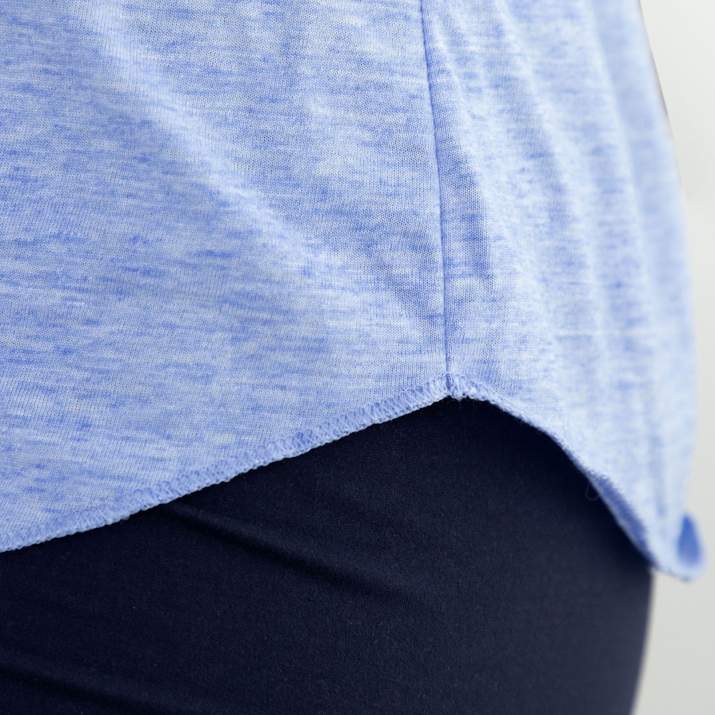 Close-up of a blue shirt hem paired with dark leggings.