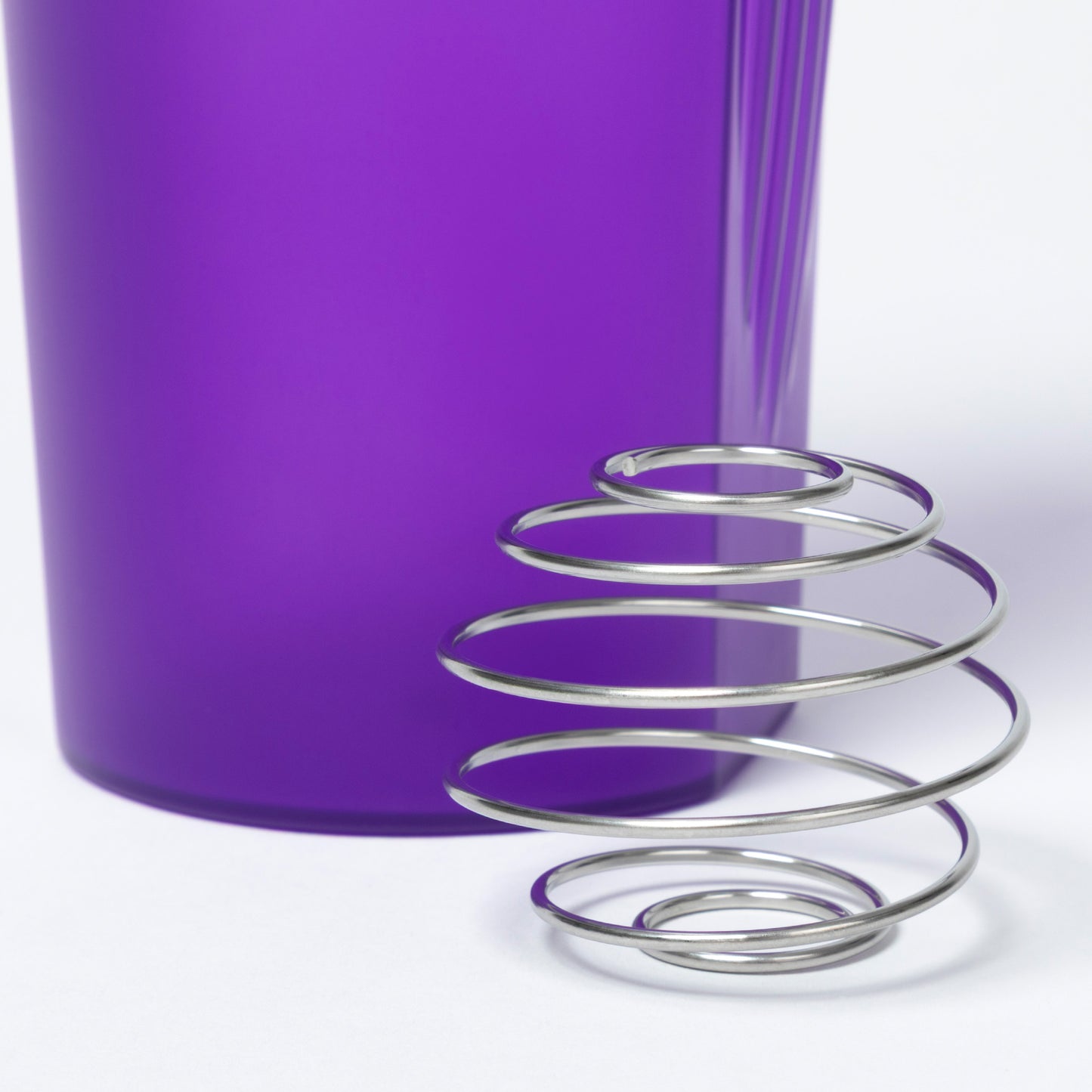 Metallic wire shaker ball with a purple tumbler in the background