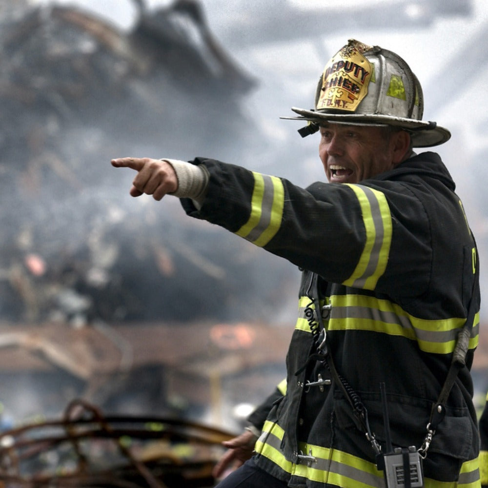 On the left, an FDNY deputy chief in turnout gear points urgently amid smoking rubble; on the right, a rescue worker with a search dog navigates debris-strewn streets.