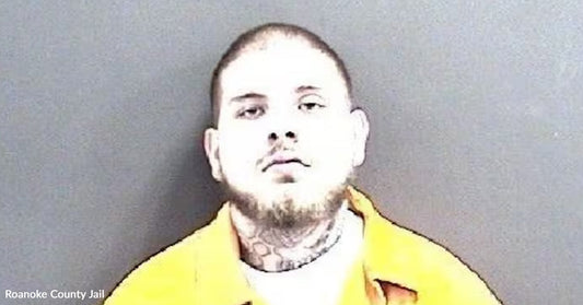 Mugshot of a man in a yellow jail uniform against a gray background.