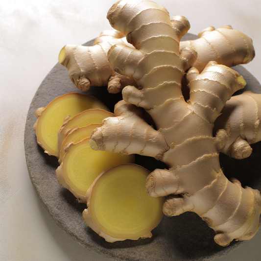 Fresh ginger root and sliced pieces on a plate.