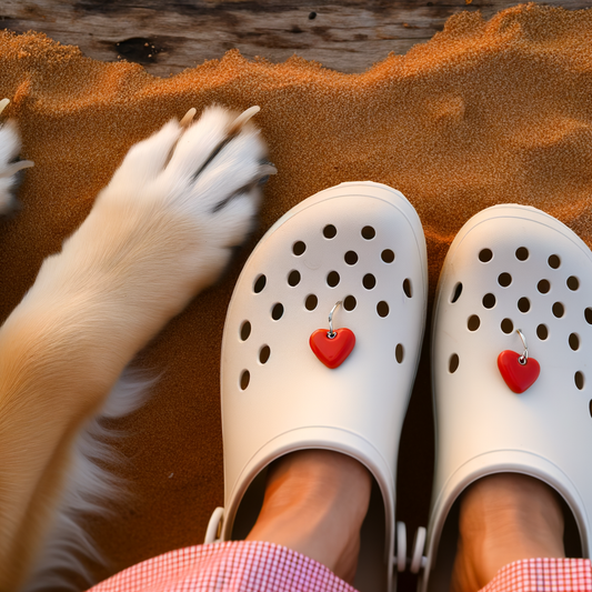 White crocs with red heart charms and a dog’s paw.