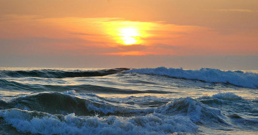 Sunset over ocean waves, creating a serene and colorful seascape.