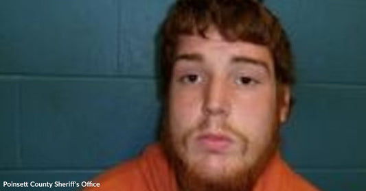 Mugshot of a young man with short reddish hair and beard wearing an orange jail shirt.