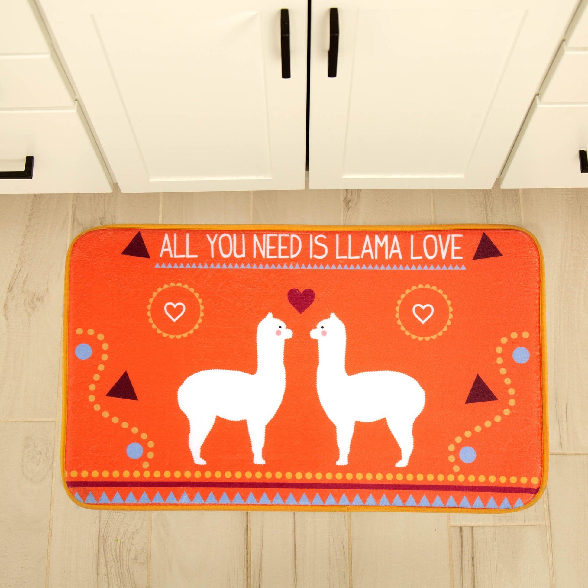 Orange rug with llamas and the phrase 'All you need is llama love' on a wooden floor.