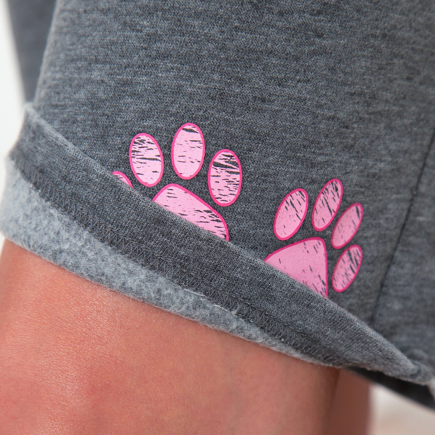 Gray shorts with pink paw prints on a person wearing them.