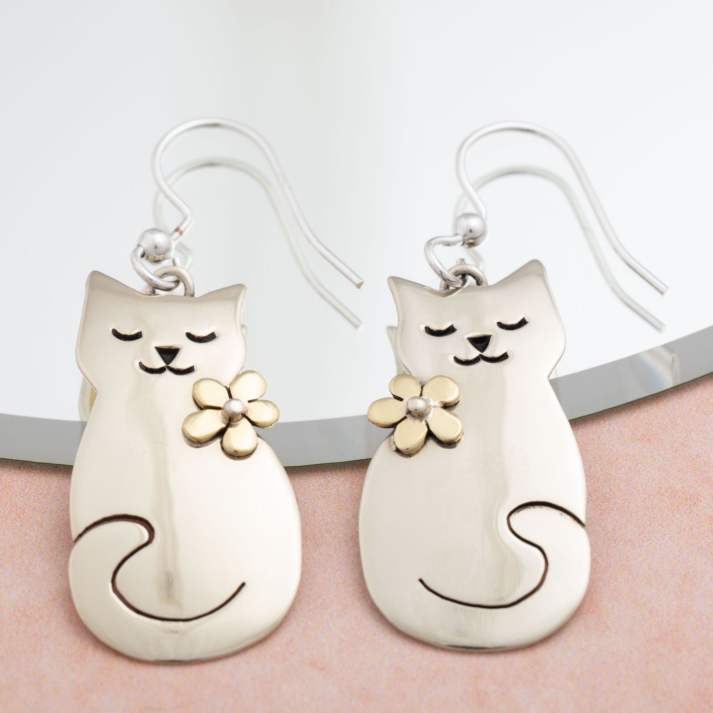 Cat-shaped earrings with floral details on a white background