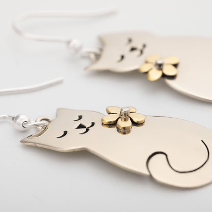Cat-shaped earrings with floral details on a light background