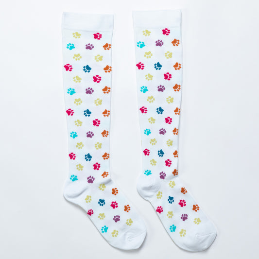 White compression socks with brightly colored paw prints all over, against a white background.