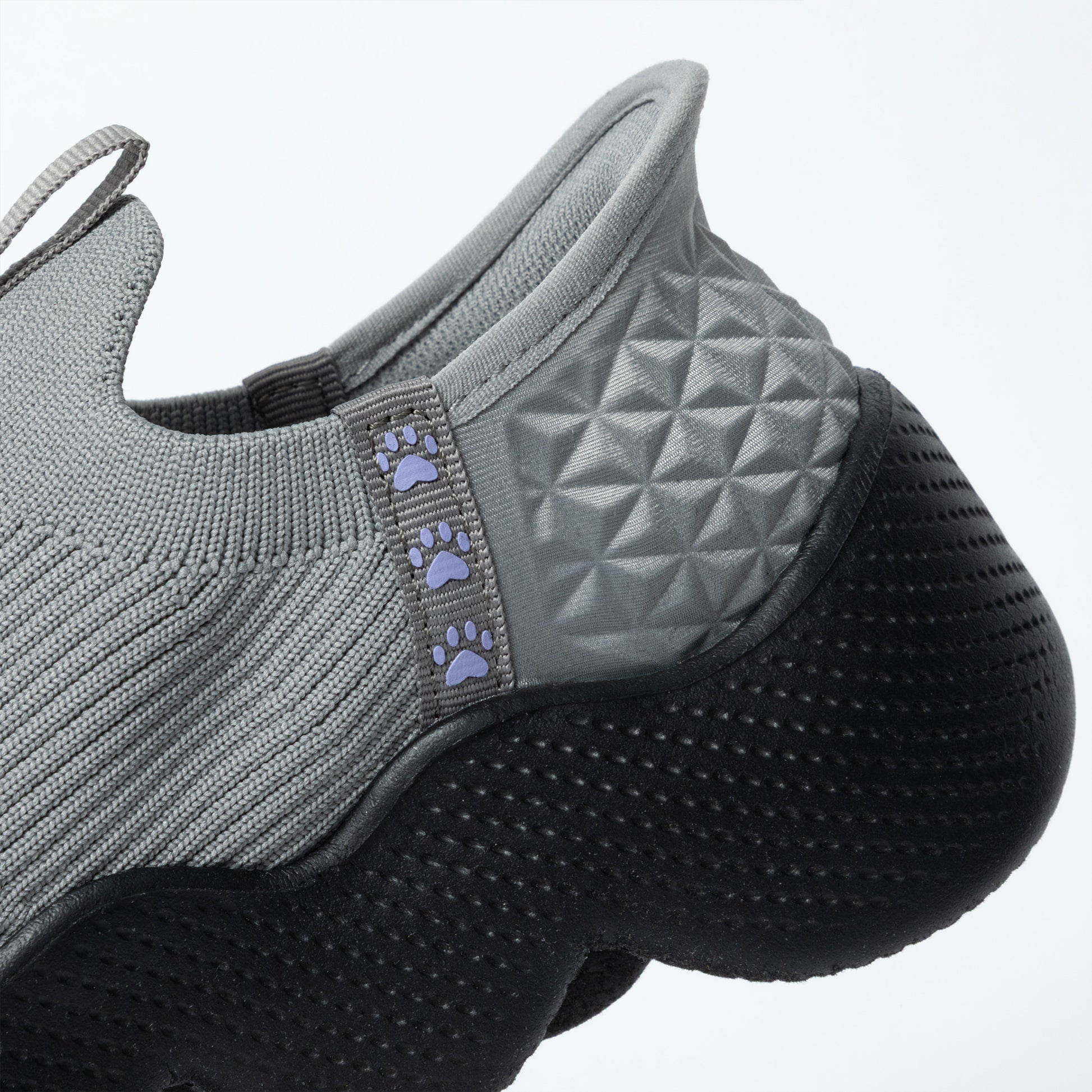 Gray slip on shoe with textured sole and paw pattern on a white background