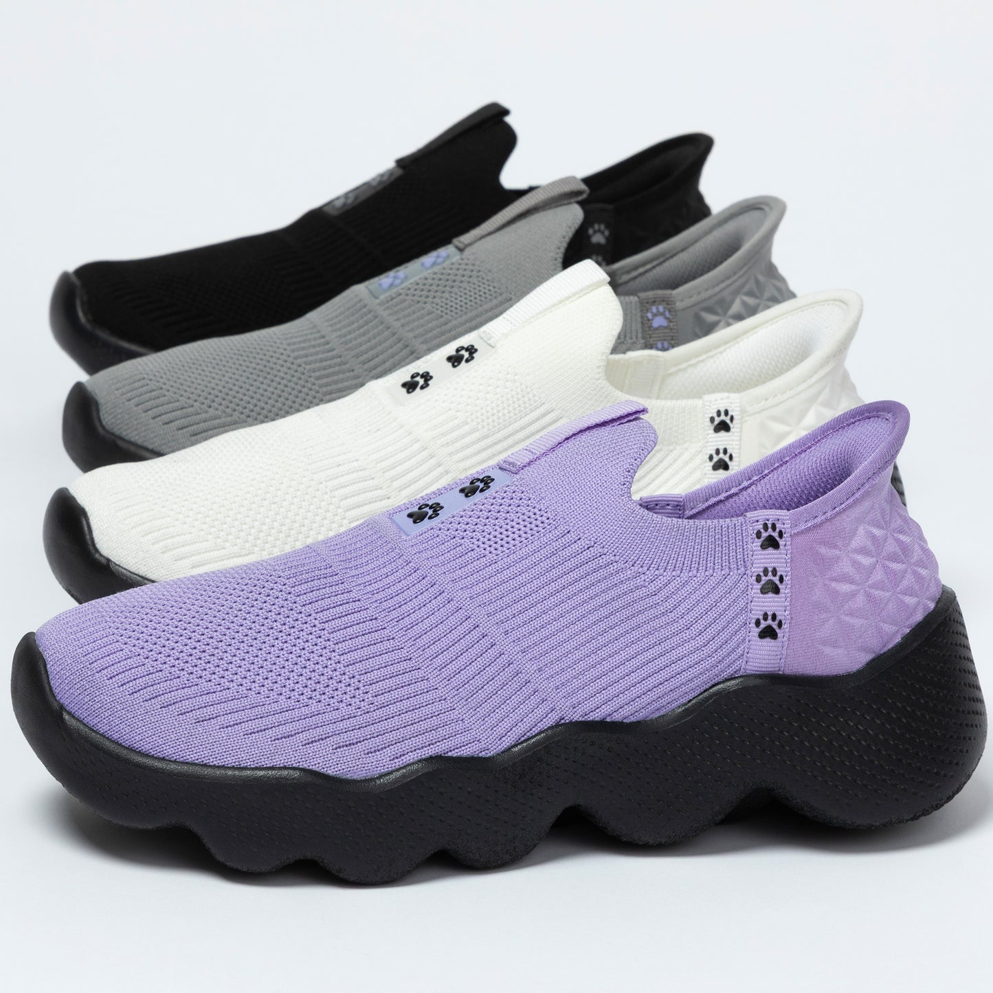 Four pairs of different color slip-on shoes with paw prints on a light gray background