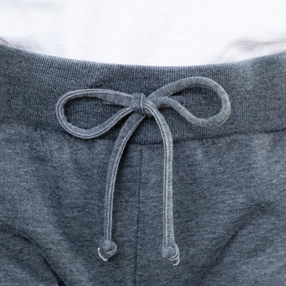 Close-up of gray sweatpants with a drawstring on a white background
