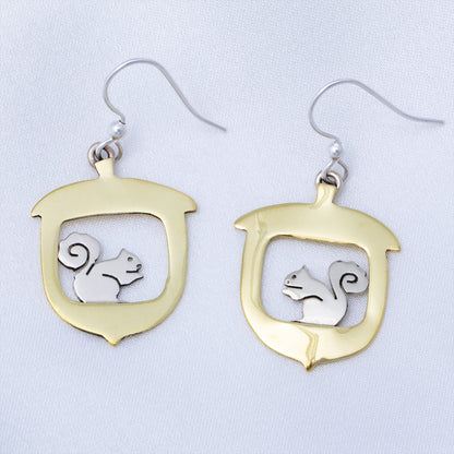 Brass and silver earrings with a squirrel design on a light gray background.
