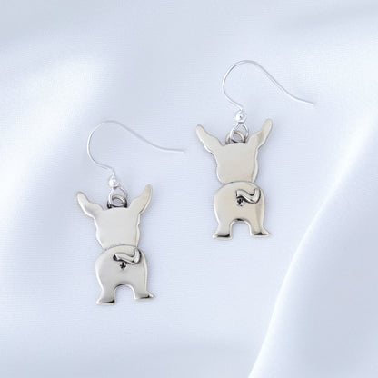 Silver dog-shaped earrings on a light gray background