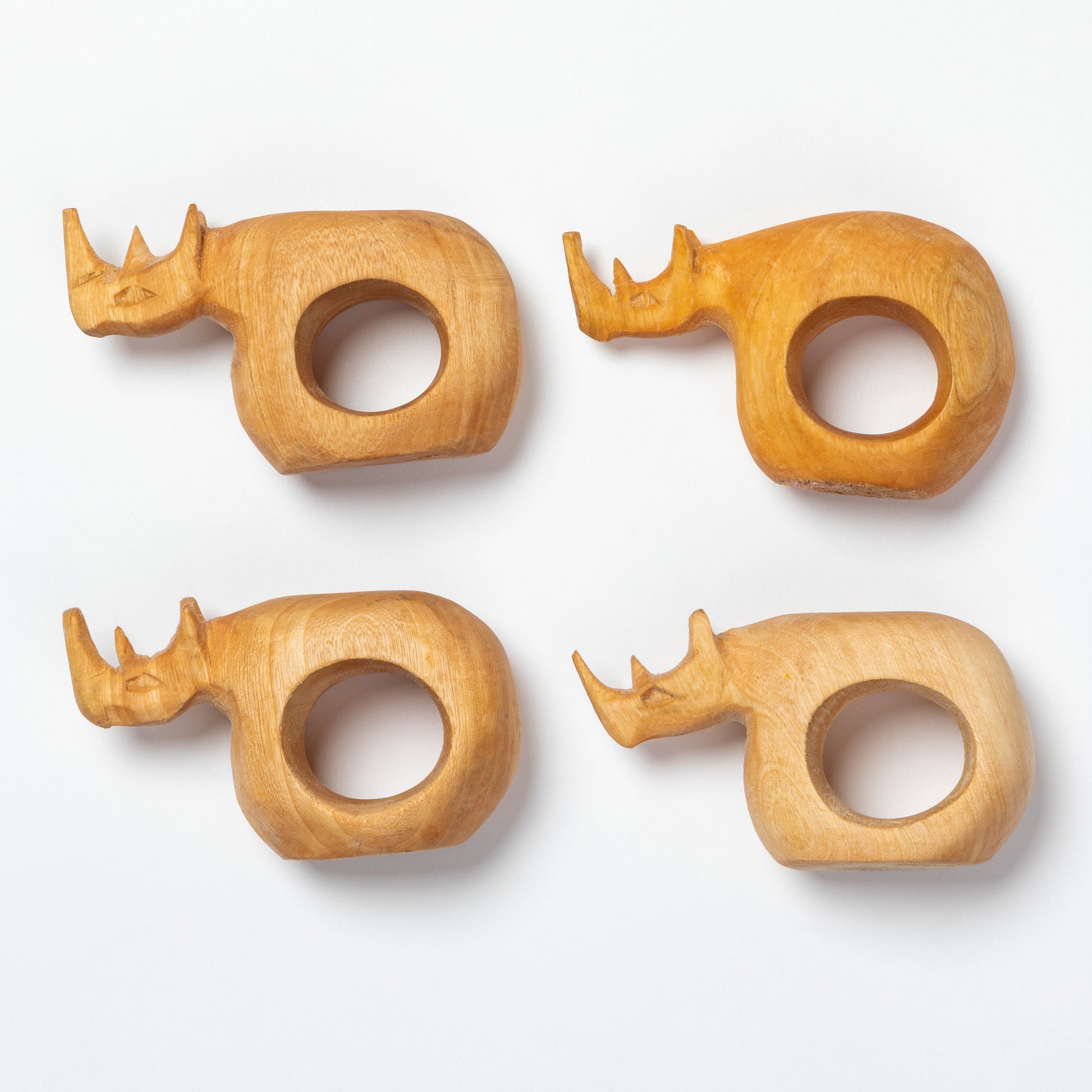 Four wooden rhino napkin rings on a white background.