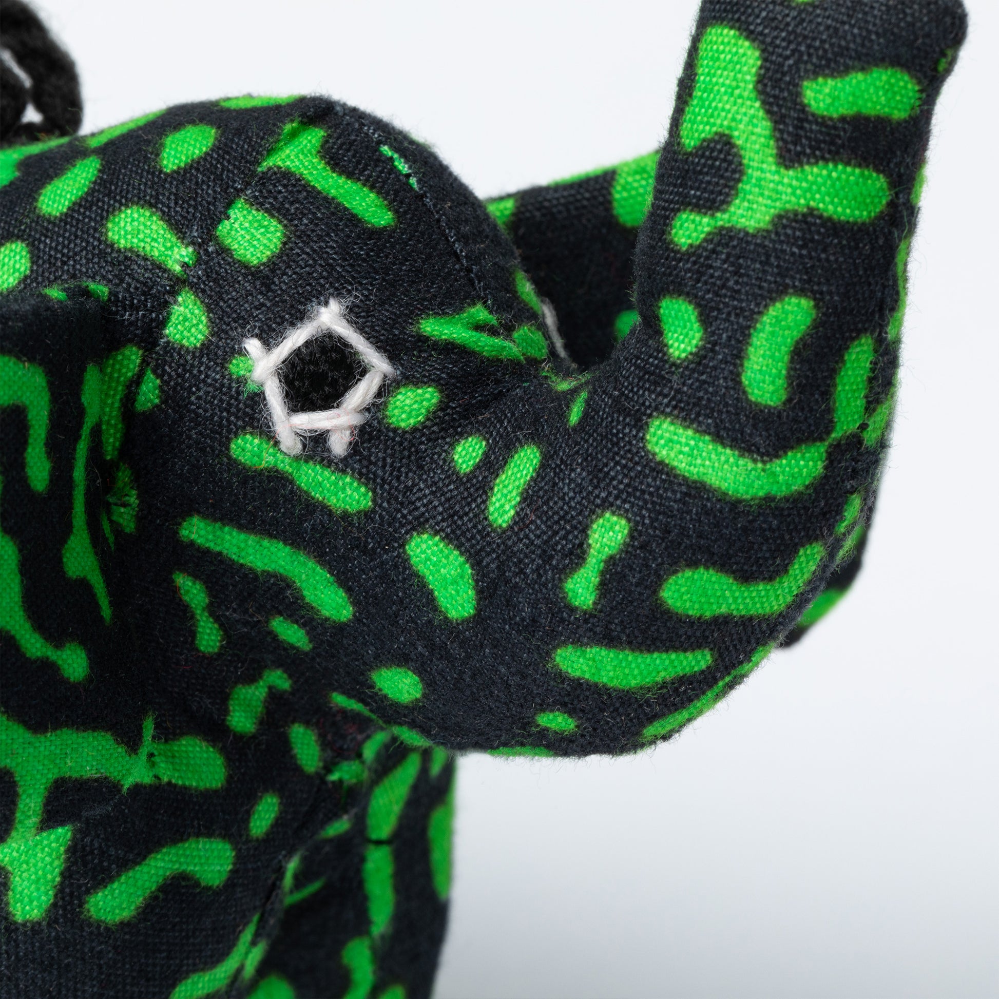 Close-up of a black and green patterned fabric elephant ornament.