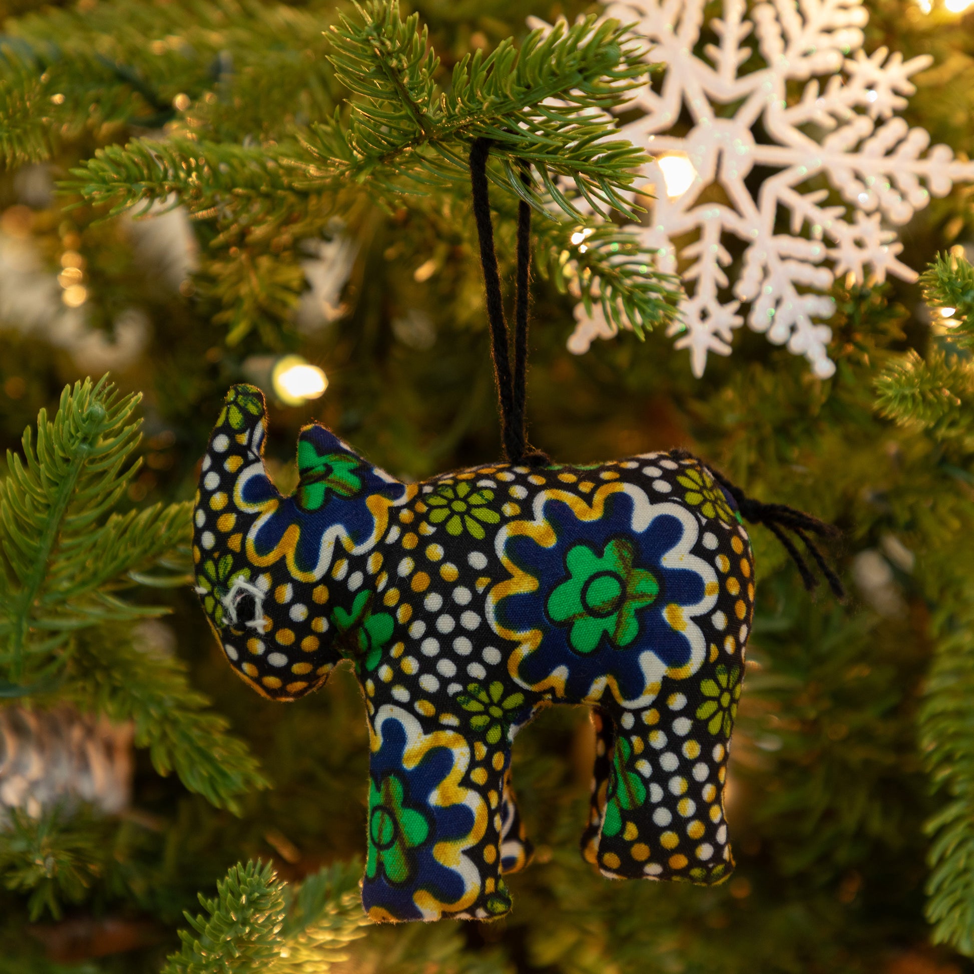 Decorative rhino ornament with floral patterns hanging on a Christmas tree.