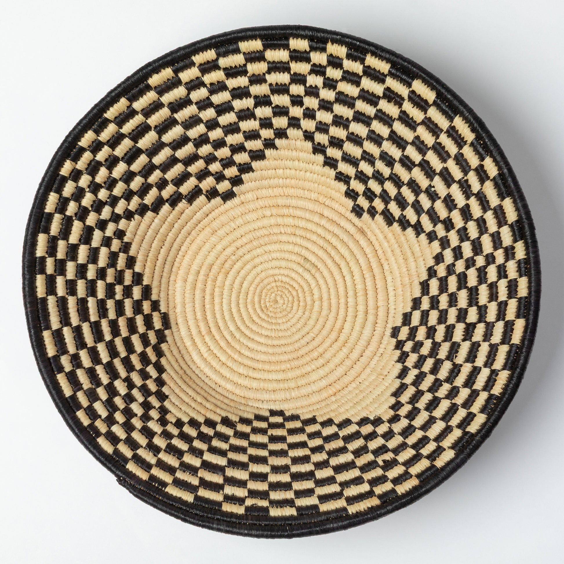 Round woven raffia basket with black and beige pattern and a star at the center, on a white background.