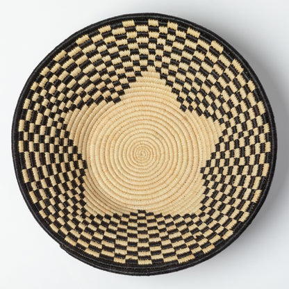 Round woven raffia basket with black and beige pattern and a star at the center, on a white background.