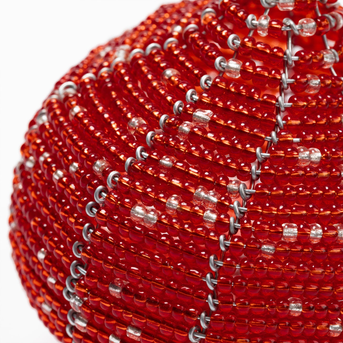 Close-up of a red beaded ball ornament with silver accents on a white background