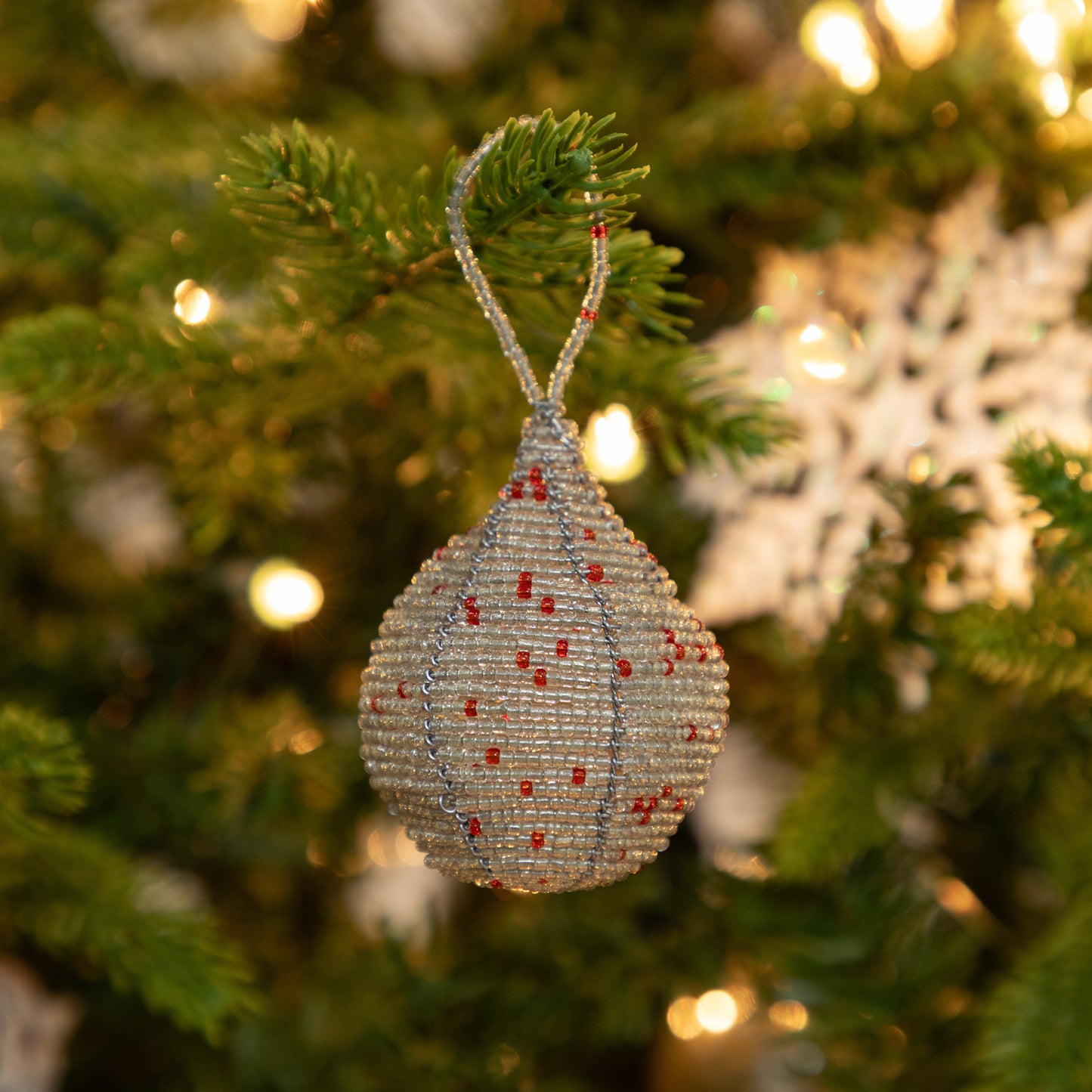 Decorative Christmas ornament on a tree with blurred lights in the background