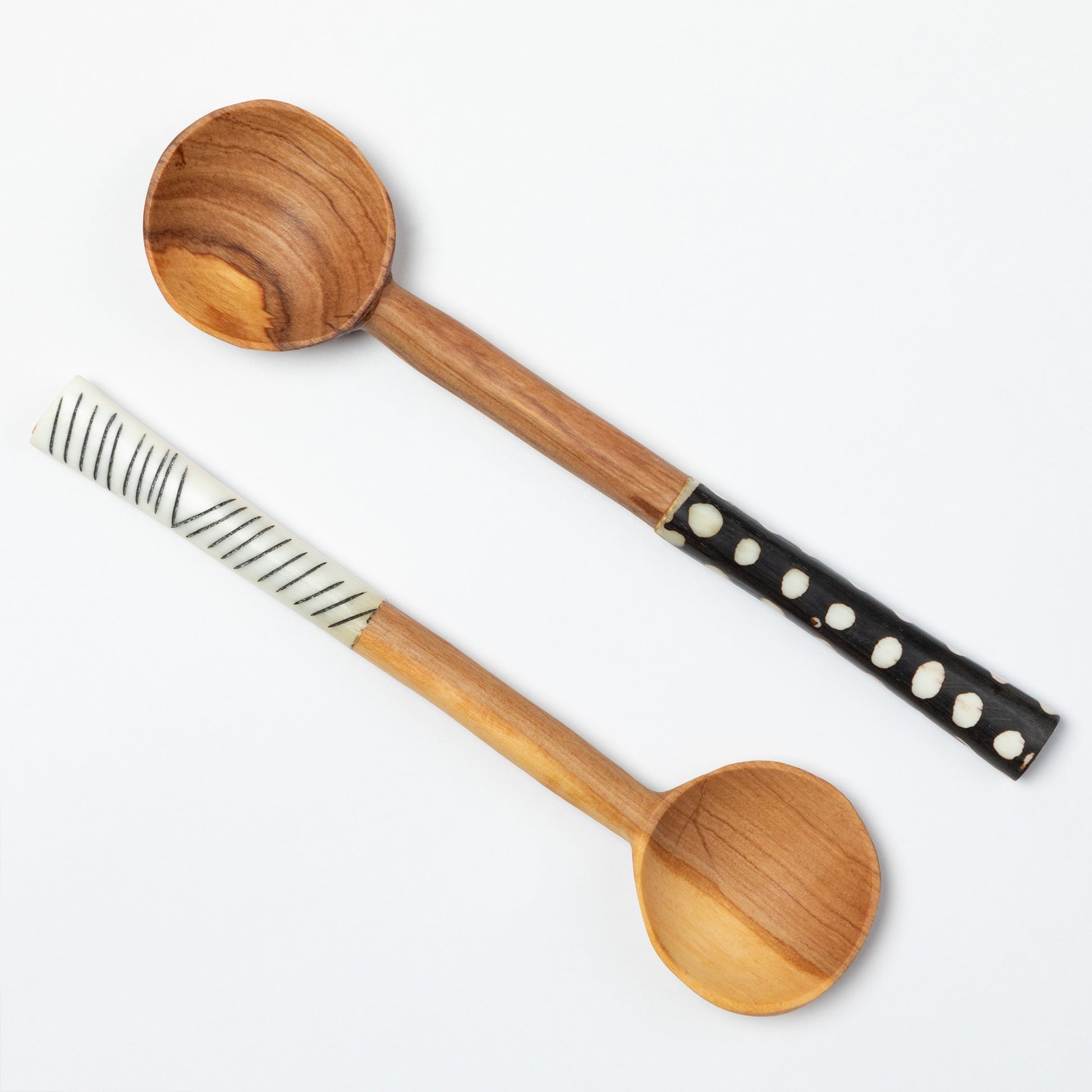Two olive wood spoons with decorative handles on a white background