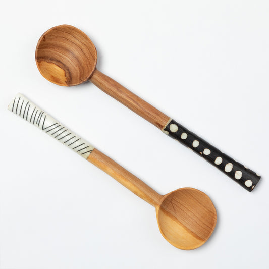 Two olive wood spoons with decorative handles on a white background