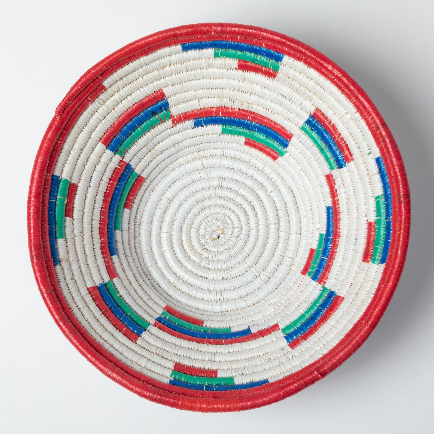 Woven basket with concentric circles of red, blue, and green on a white background