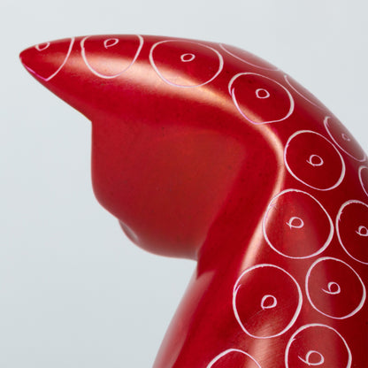 Red soapstone cat figurine with white circular patterns on a white background