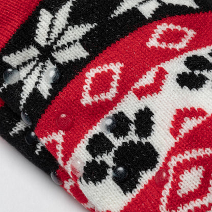 close up detail Pair of red, black white Sherpa Fleece Lined Paw Print Cabin Slipper Socks with sherpa trim on a light gray background alpine fair isle paws red with the traction dots