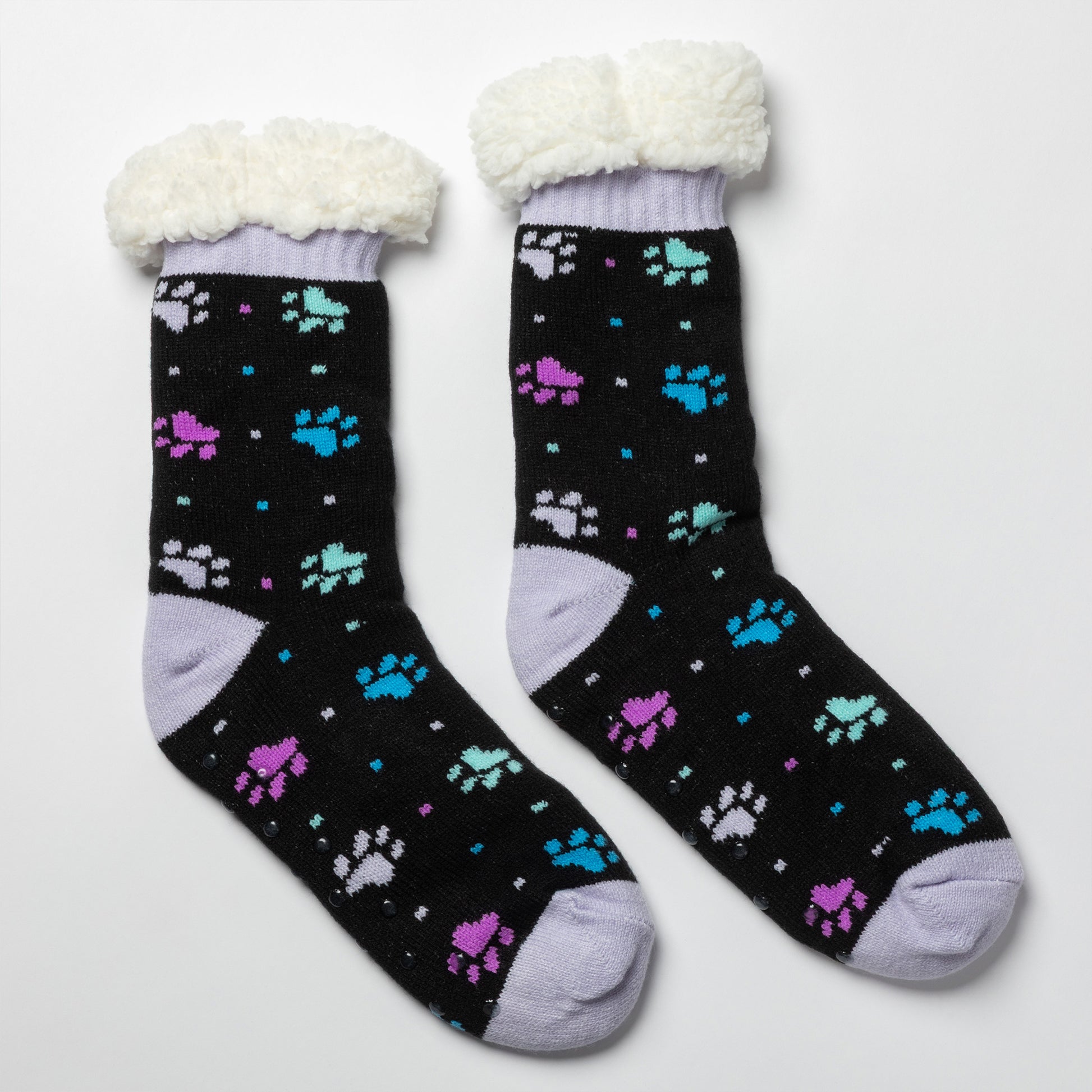 Pair of black with purple and blue polka dot paws Sherpa Fleece Lined Paw Print Cabin Slipper Socks with sherpa trim on a light gray background polka dot paws 