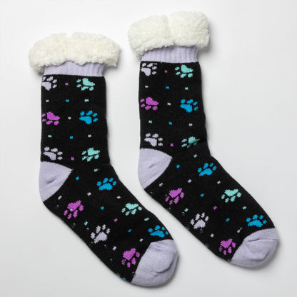 Pair of black with purple and blue polka dot paws Sherpa Fleece Lined Paw Print Cabin Slipper Socks with sherpa trim on a light gray background polka dot paws 