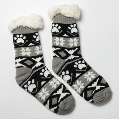 Pair of gray, black white Sherpa Fleece Lined Paw Print Cabin Slipper Socks with sherpa trim on a light gray background alpine fair isle paws black