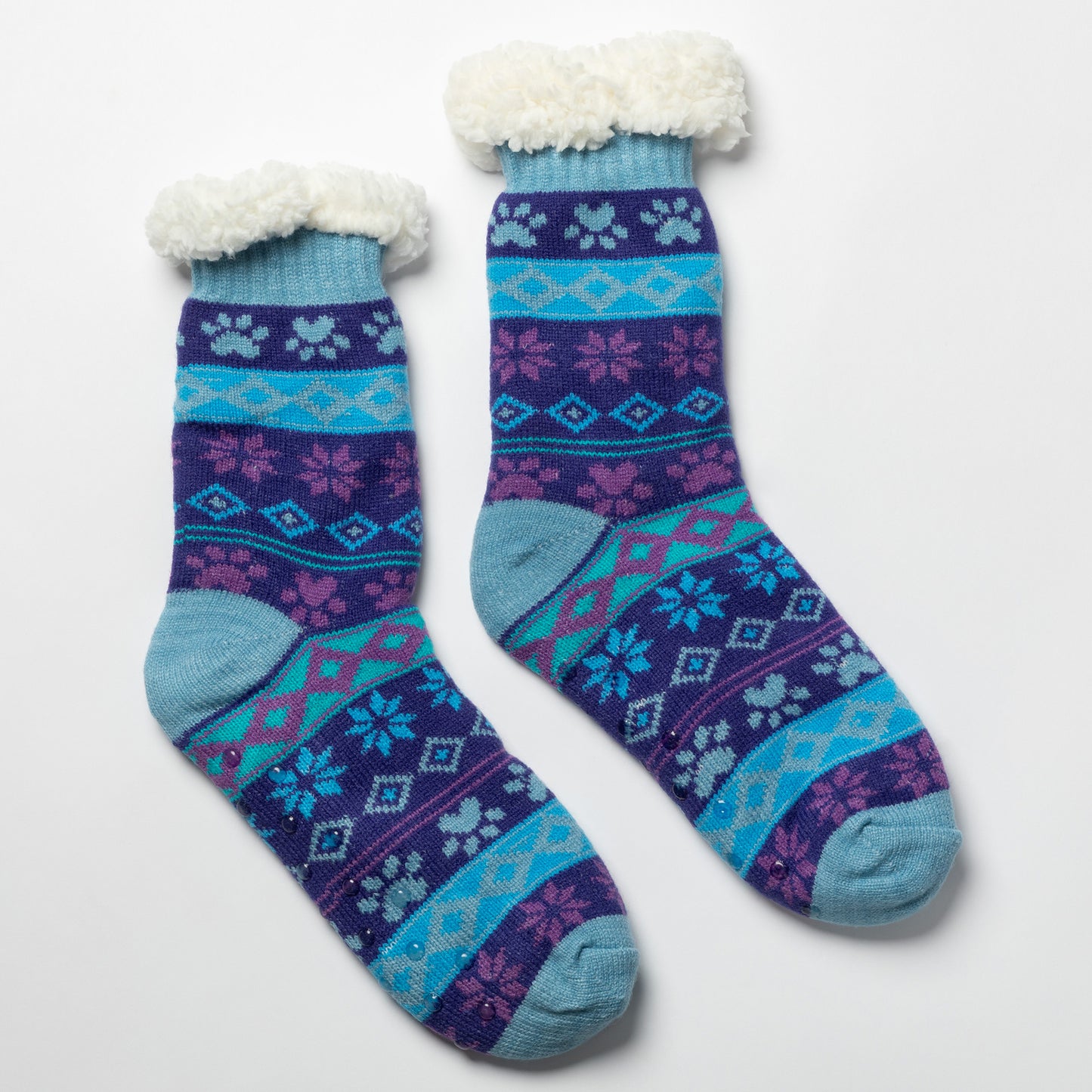 Pair of blue and purple Sherpa Fleece Lined Paw Print Cabin Slipper Socks with sherpa trim  on a light gray background arctic paws pattern