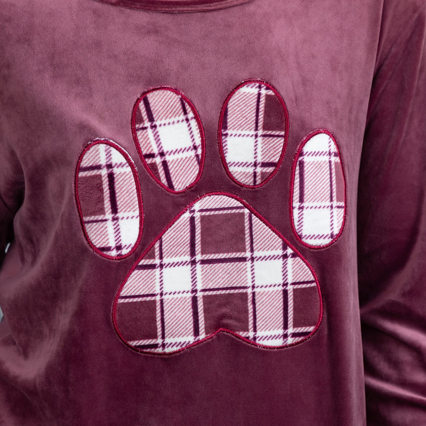 Soft texture of the velour shirt. The plaid paw print is also made of the same fabric. There is red piping outlining the paw print. 