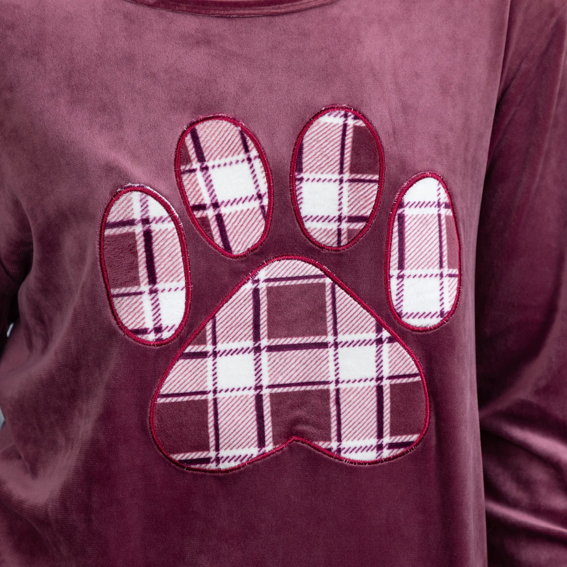 Soft texture of the velour shirt. The plaid paw print is also made of the same fabric. There is red piping outlining the paw print. 