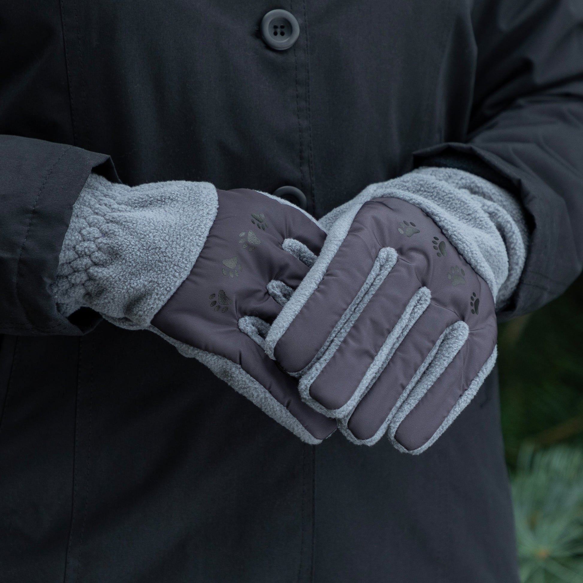 Person wearing dark gray gloves with fleece lining inside a black coat.
