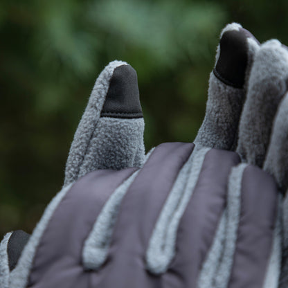 Close-up of gray gloves with textured palm and fingers against a blurred green background